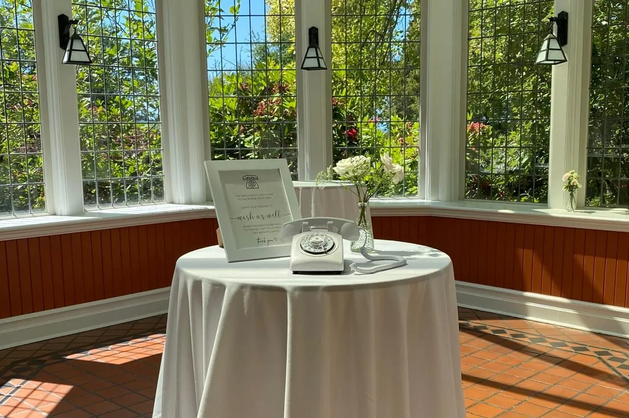 Audio guest book with a white rotary phone and a framed sign on a cocktail table in a sunlit window room
