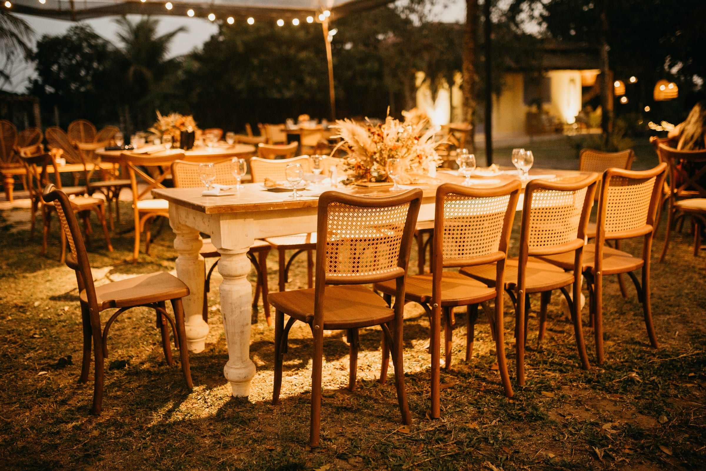 An outdoor reception table set under festoon lights at dusk