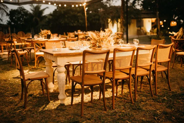 An outdoor reception table set under festoon lights at dusk