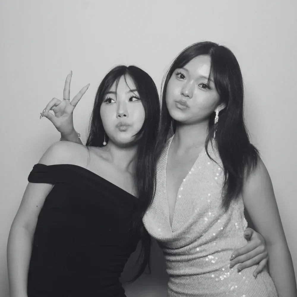 Two guests in evening dresses posing for a black and white glam booth portrait