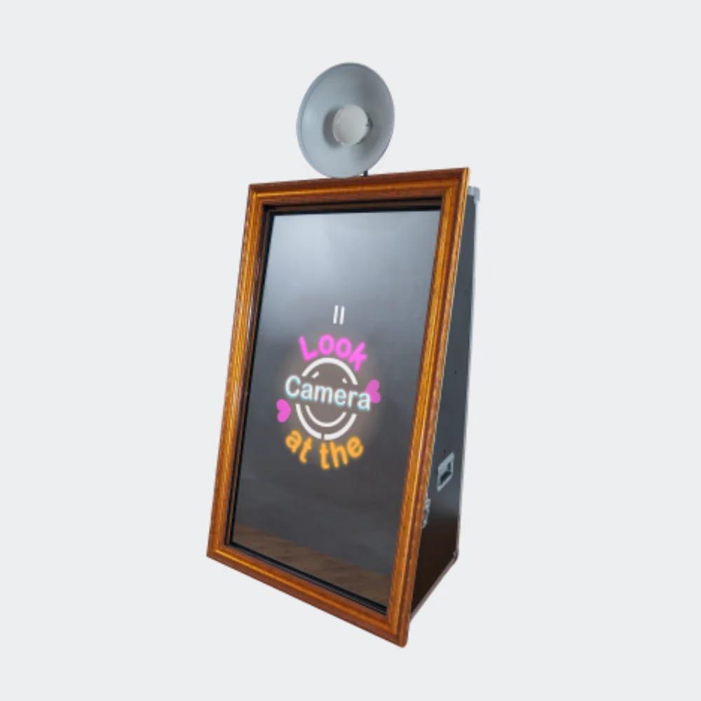 Mirror photo booth with a wooden frame and ring light showing a Look at the Camera animation on the screen.
